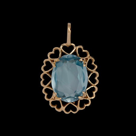Vintage 9ct yellow gold pendant with oval faceted blue topaz, approx 3.5ct, set in an openwork heart motif frame, Birmingham 1995 hallmark, front view on black background